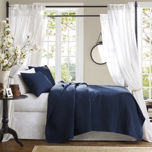 bed with white and blue pillows and blanket