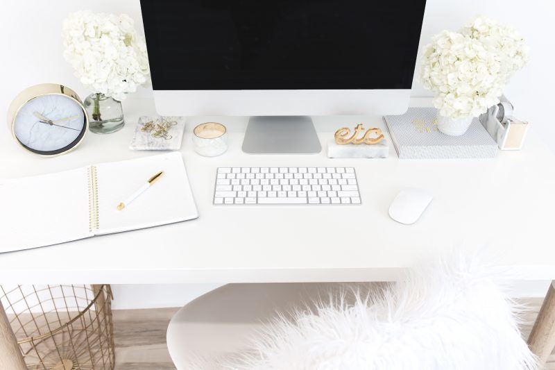 white table with mac, notebook and flowers on top