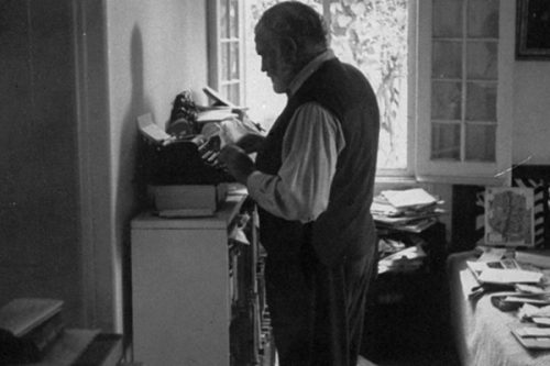 Ernest Hemingway working while standing at typewriter