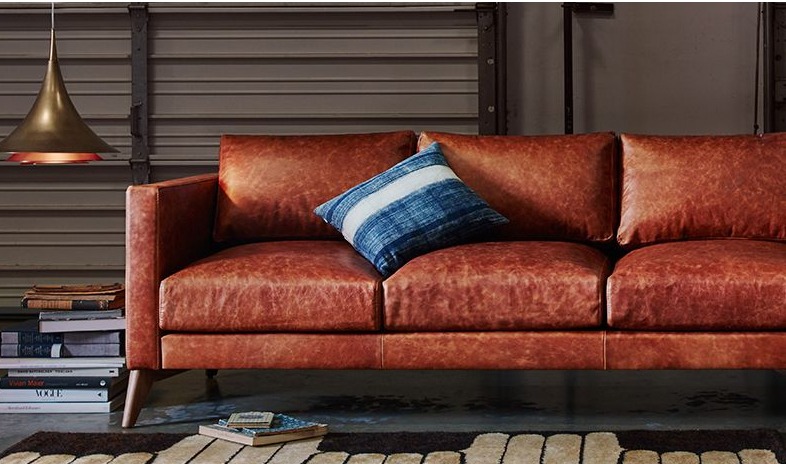 red leather sofa with a blue throw pillow and books on the side