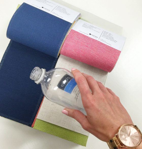 hand holding a bottle and some fabric samples
