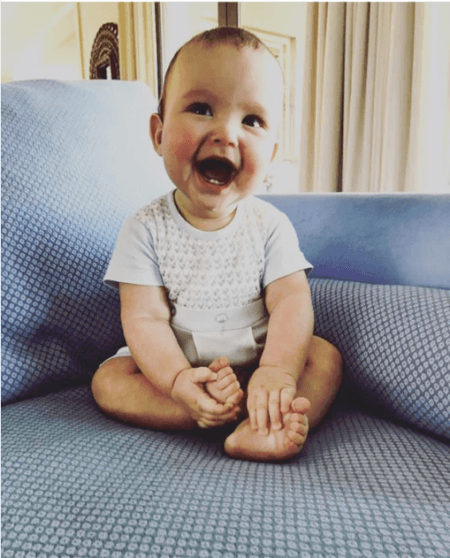 a smiling baby sitting in a sofa