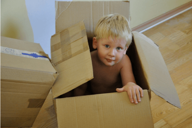 a boy in a moving to a new house in a box 